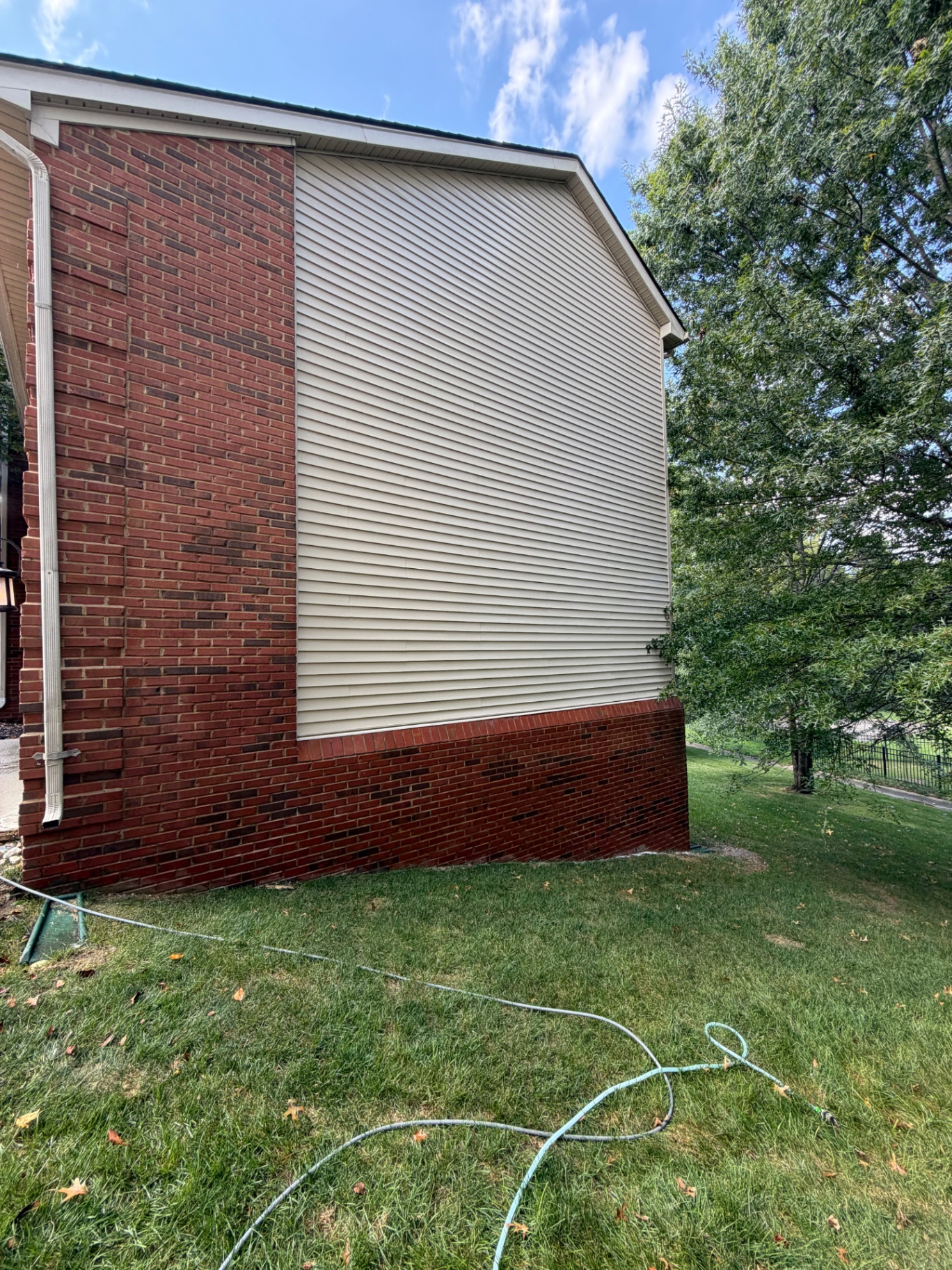 Before and after of a soft wash on vinyl siding and brick